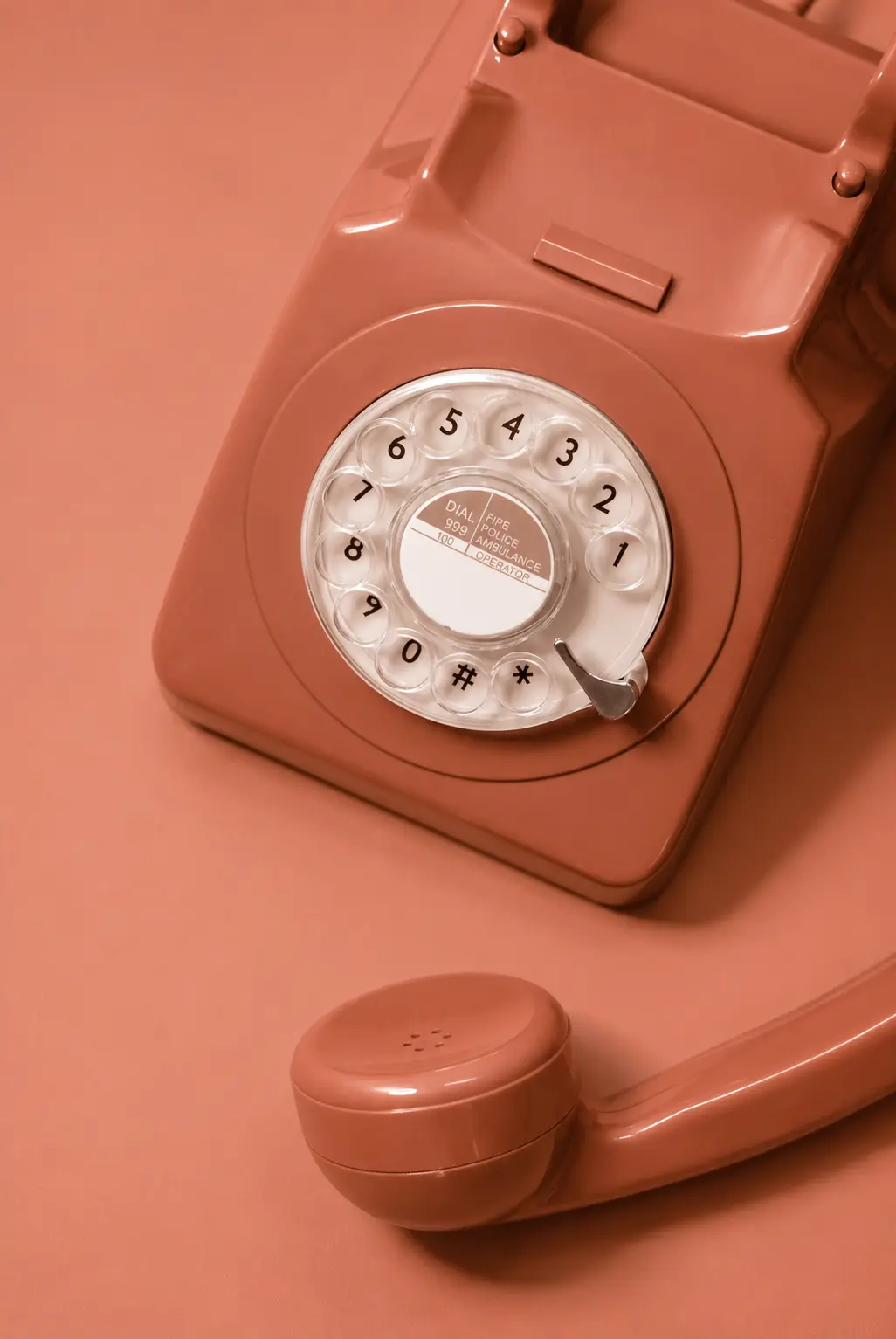 Coral-pink rotary telephone with handset, viewed from above