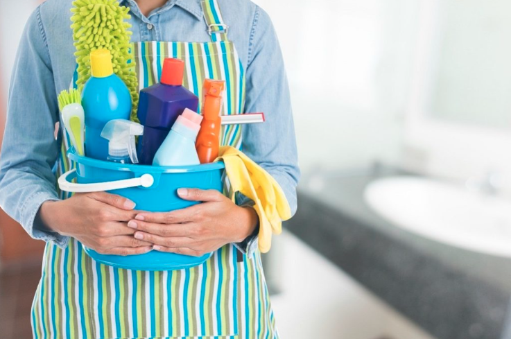 Person holding a bucket of cleaning supplies