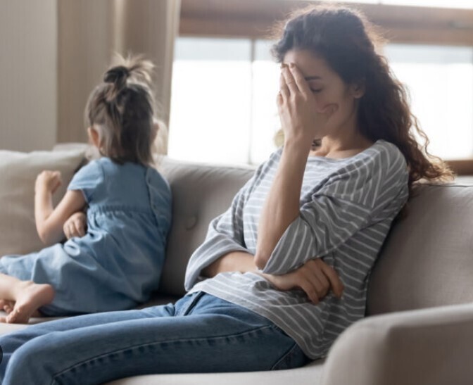 A stressed woman on the sofa with her child