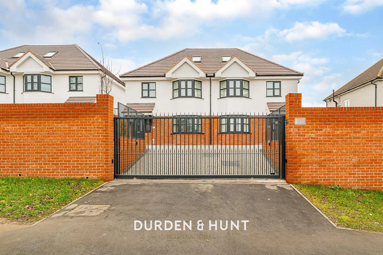 Modern white house with brick boundary walls and black metal gates, branded "Durden & Hunt"