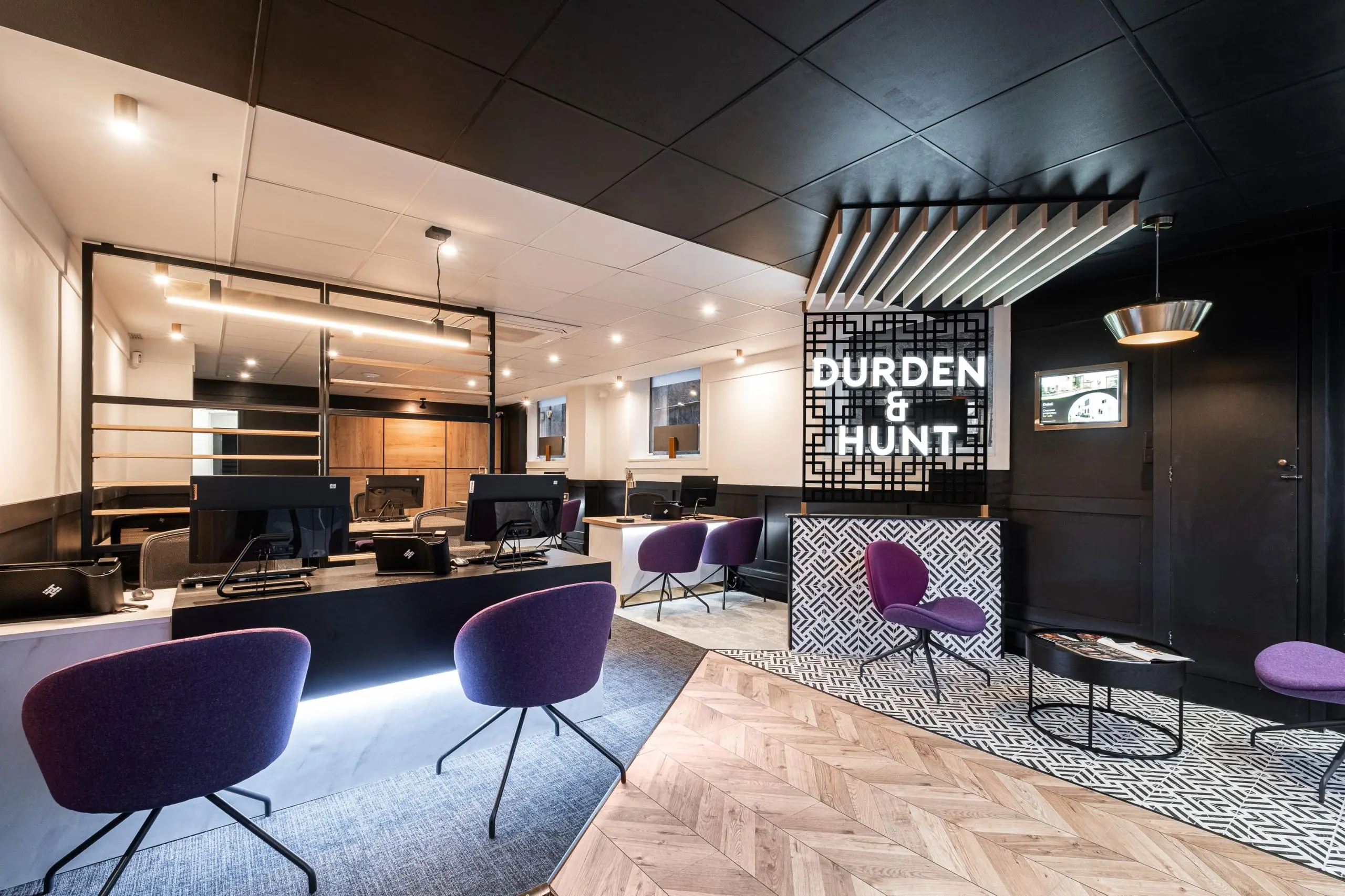 Modern office interior with purple chairs, computer desks, and a reception desk with "Burden & Hunt" signage