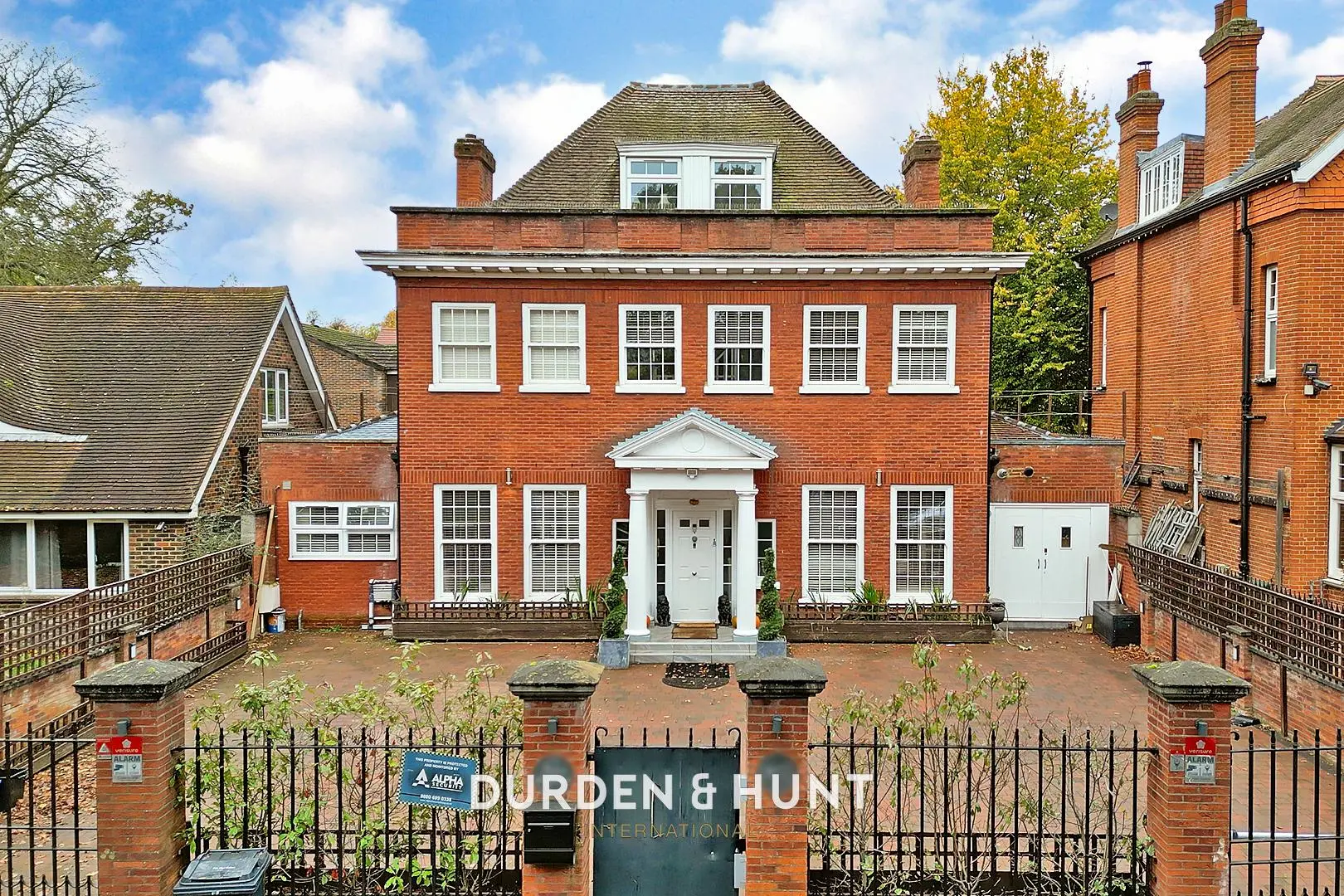 Red brick Georgian-style detached house with white sash windows, mansard roof, and white columned entrance portico