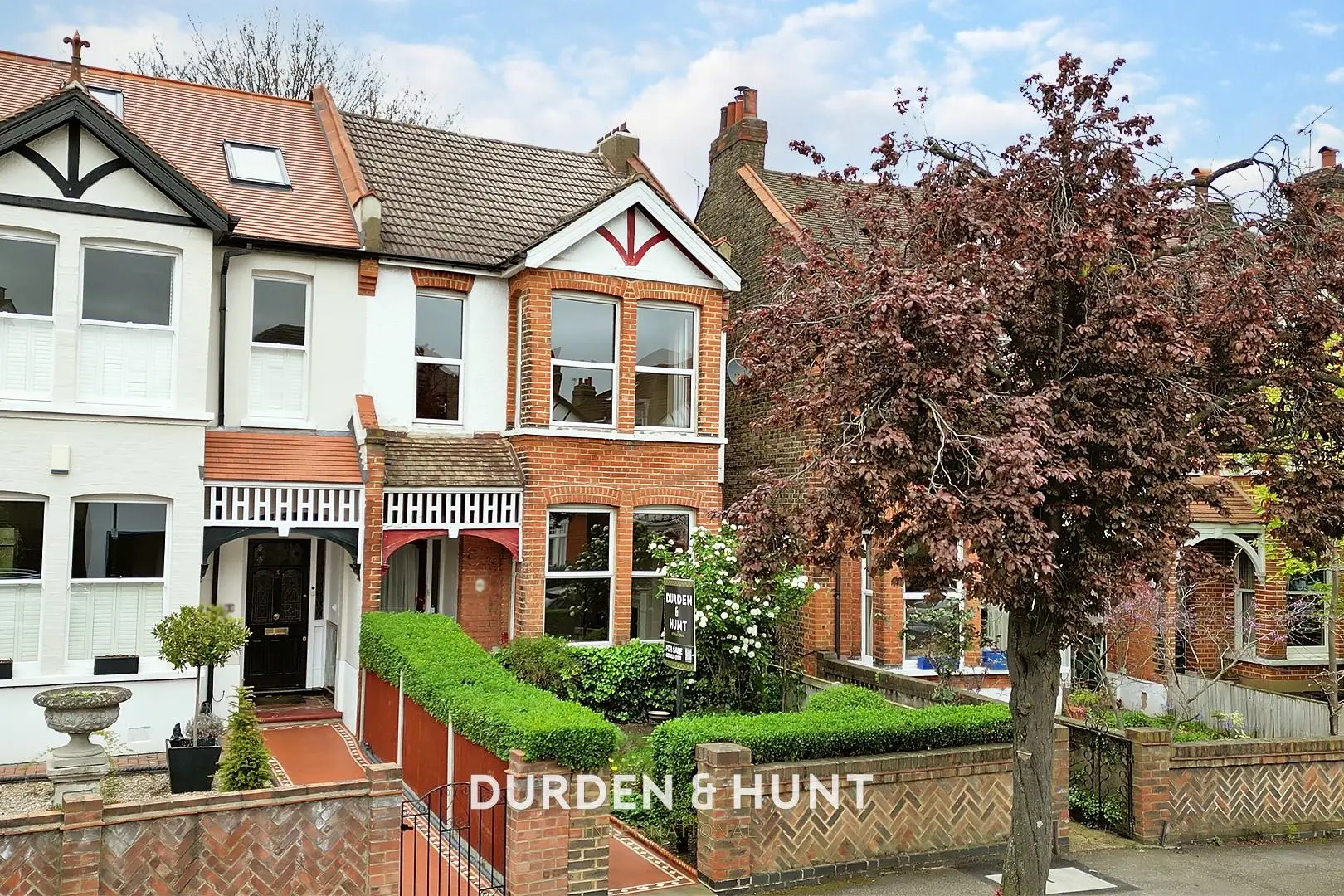 Terraced brick houses with white and cream rendered sections, bay windows, and ivy-covered walls. Estate agency branding "DURDEN & HUNT" visible at bottom.