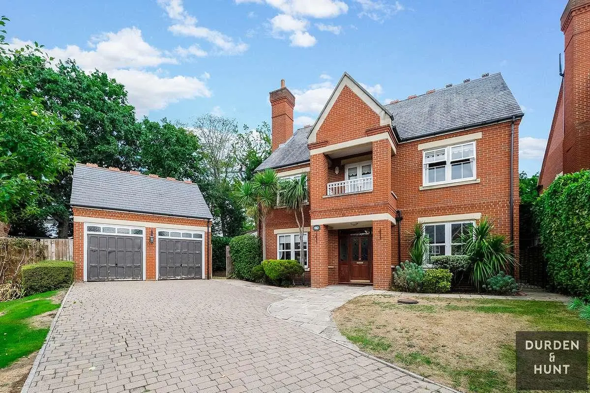 Red brick detached house with slate roof, double garage, and paved driveway