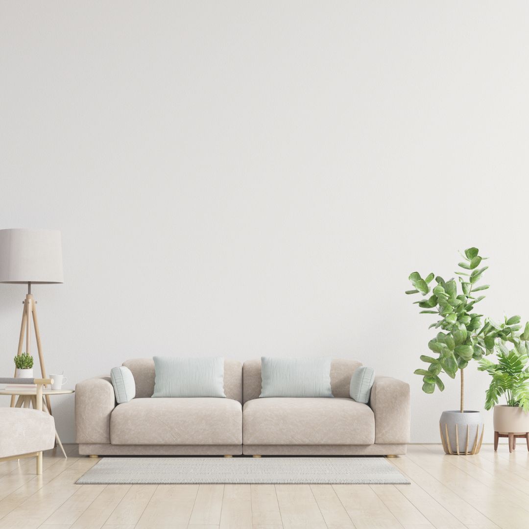 Bright, neutral living room with a beige sofa, light wooden flooring, and indoor plants creating a clean, modern space