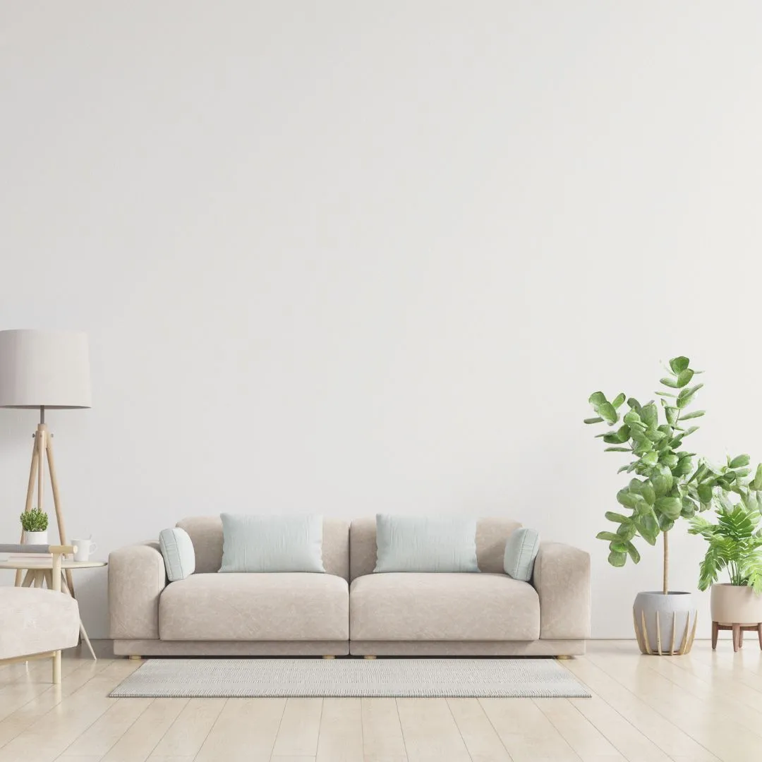 Bright, neutral living room with a beige sofa, light wooden flooring, and indoor plants creating a clean, modern space