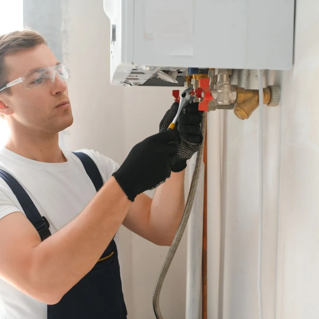 Engineer carrying out maintenance on a boiler system, checking pipes and fittings for safety and functionality